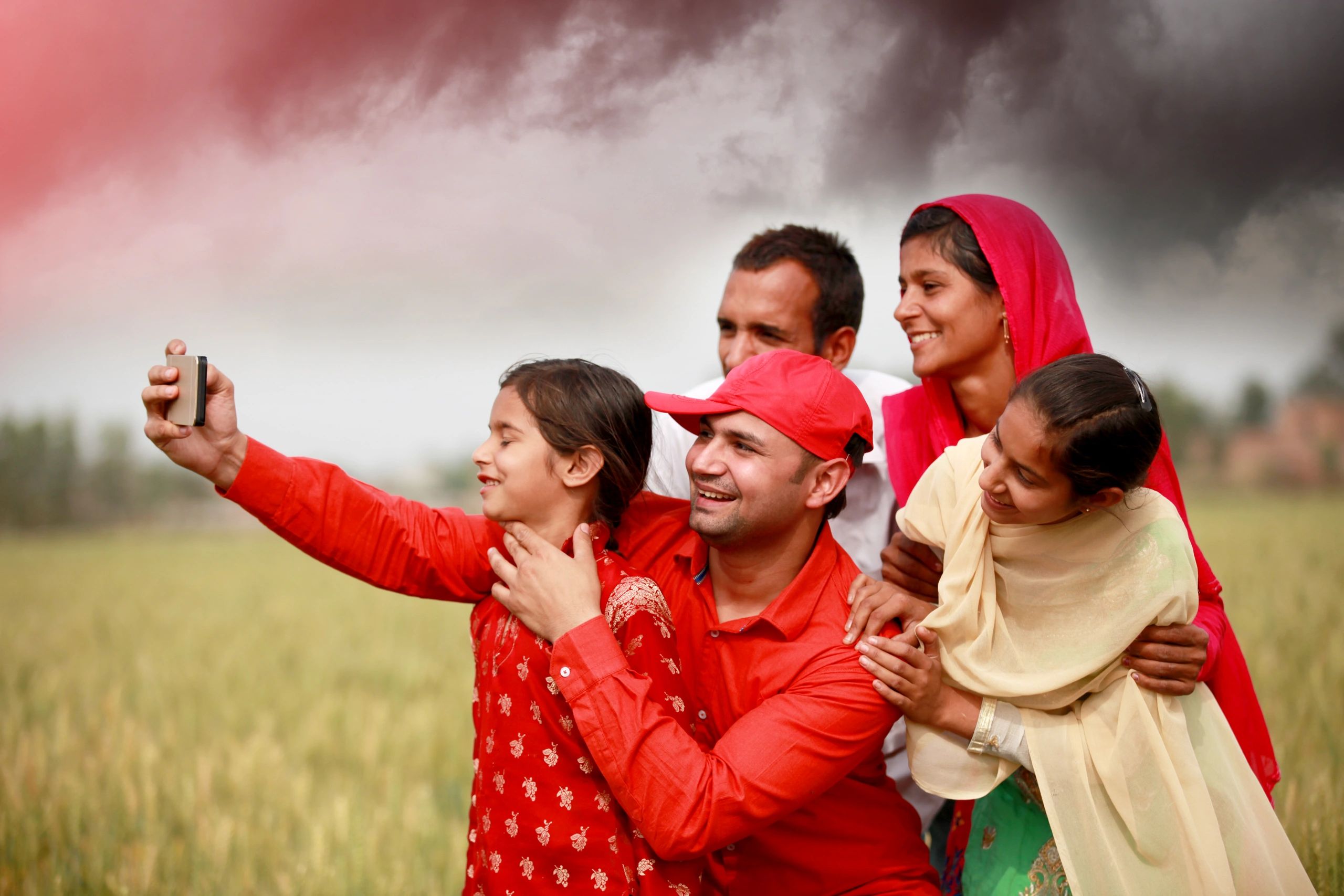 Cheerful Indian farmer family taking a selfie near green fields