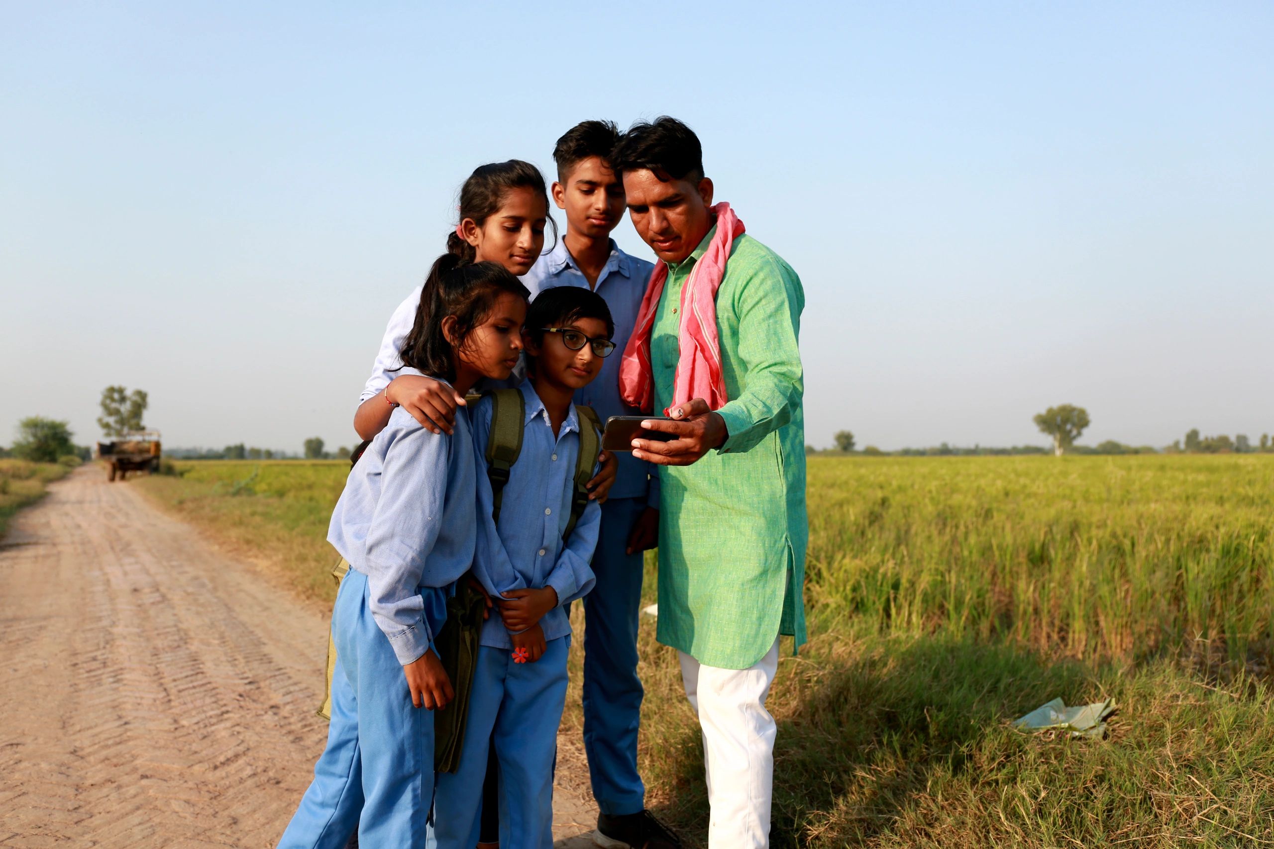 Farmer family using a mobile phone near green fields in India